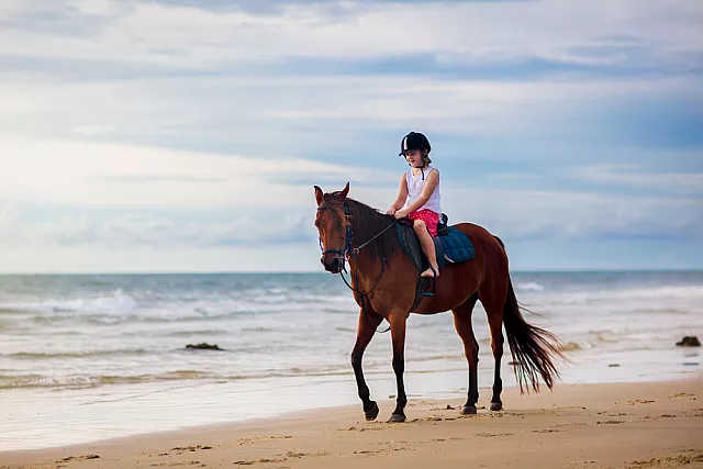 Bambino a cavallo sulla spiaggia